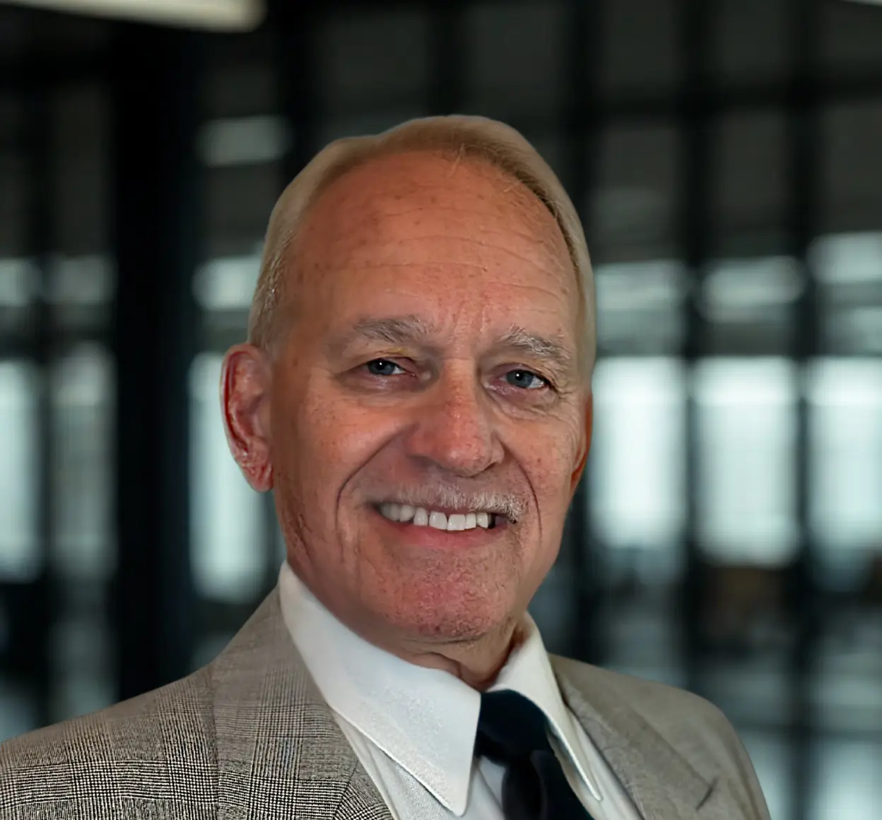 Elderly man smiling in formal attire.